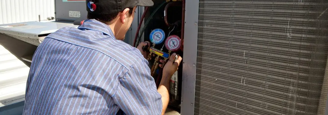 HVAC technician servicing a condenser unit in Mukwonago